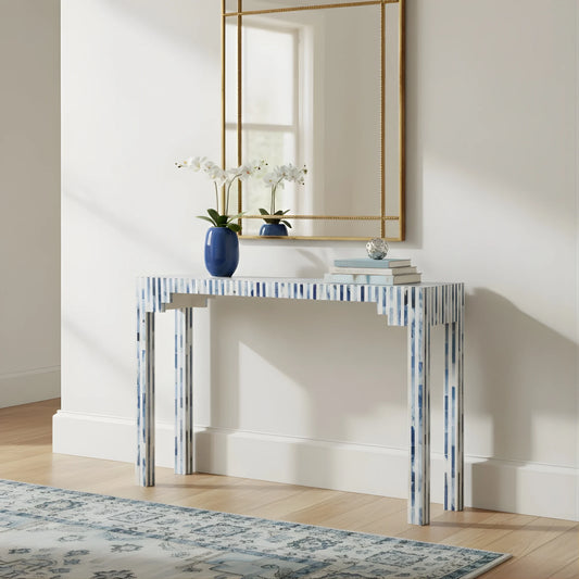 Console table with decorative items in a room with a mirror and rug.