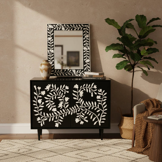 A black cabinet with bone inlay floral design, featuring two doors and a mirror with a floral pattern on the cabinet doors.