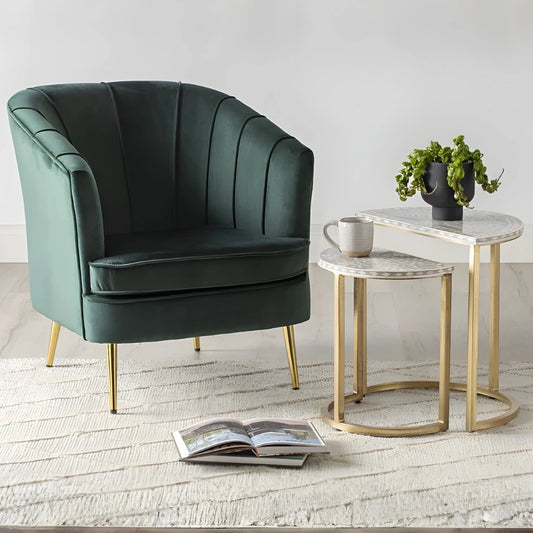 Green armchair with side tables and a plant in a minimalistic room.