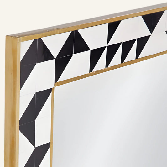 Decorative mirror with geometric black and white pattern and gold frame on a white background
