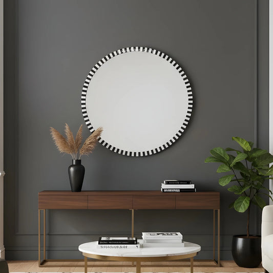 Round mirror with black and white striped frame above a wooden console table in a room.