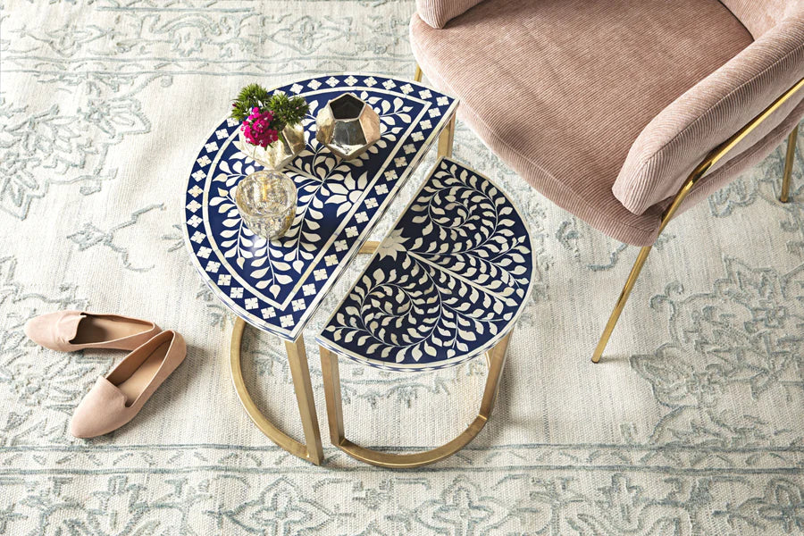 Side table with blue and white pattern next to a chair on a patterned floor.