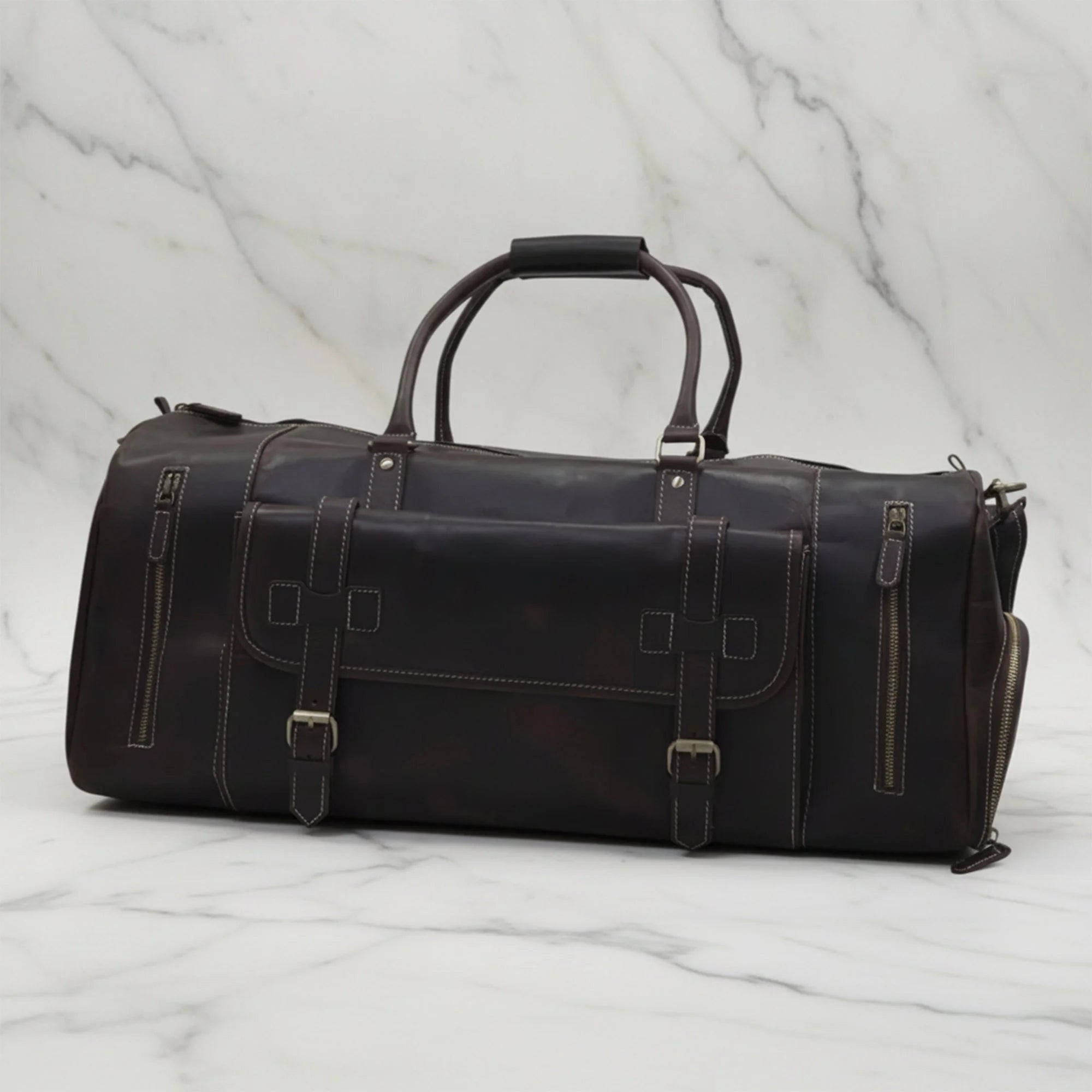 Front of the Miguel dark brown leather duffle bag showing twin top handles, buckle straps and zippered pockets